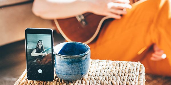 Person playing a guitar while being recorded on a mobile device